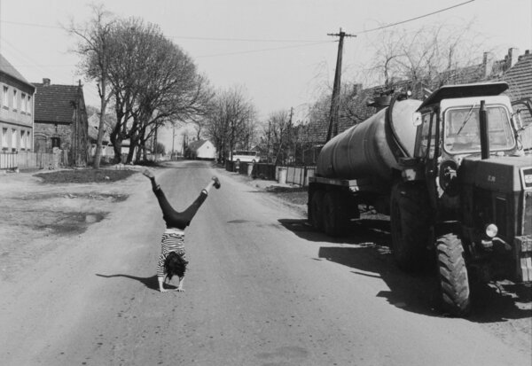 2-M151-A1-1987-1Handstand auf Dorfstrasse, BeerfeldeKind / Spiele:- Maedchen beim Handstand auf einer Dorf-strasse in Beerfelde (Brandenburg, DDR).-Foto, 1987. Aus der Serie: Bilder ausBeerfelde.